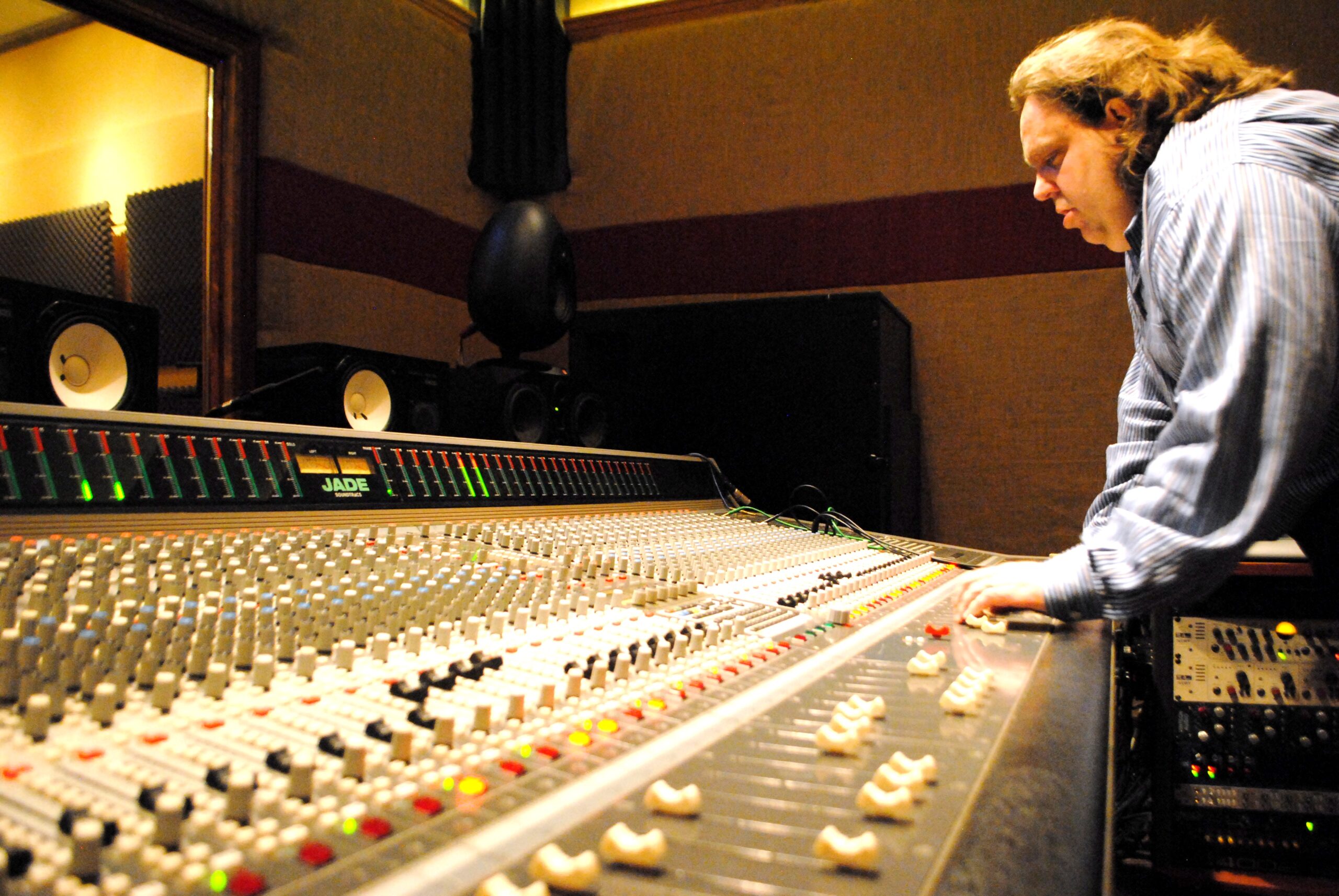 Joey Stuckey standing at the Shadow Sound Studio mixing desk with his hand on a fader.