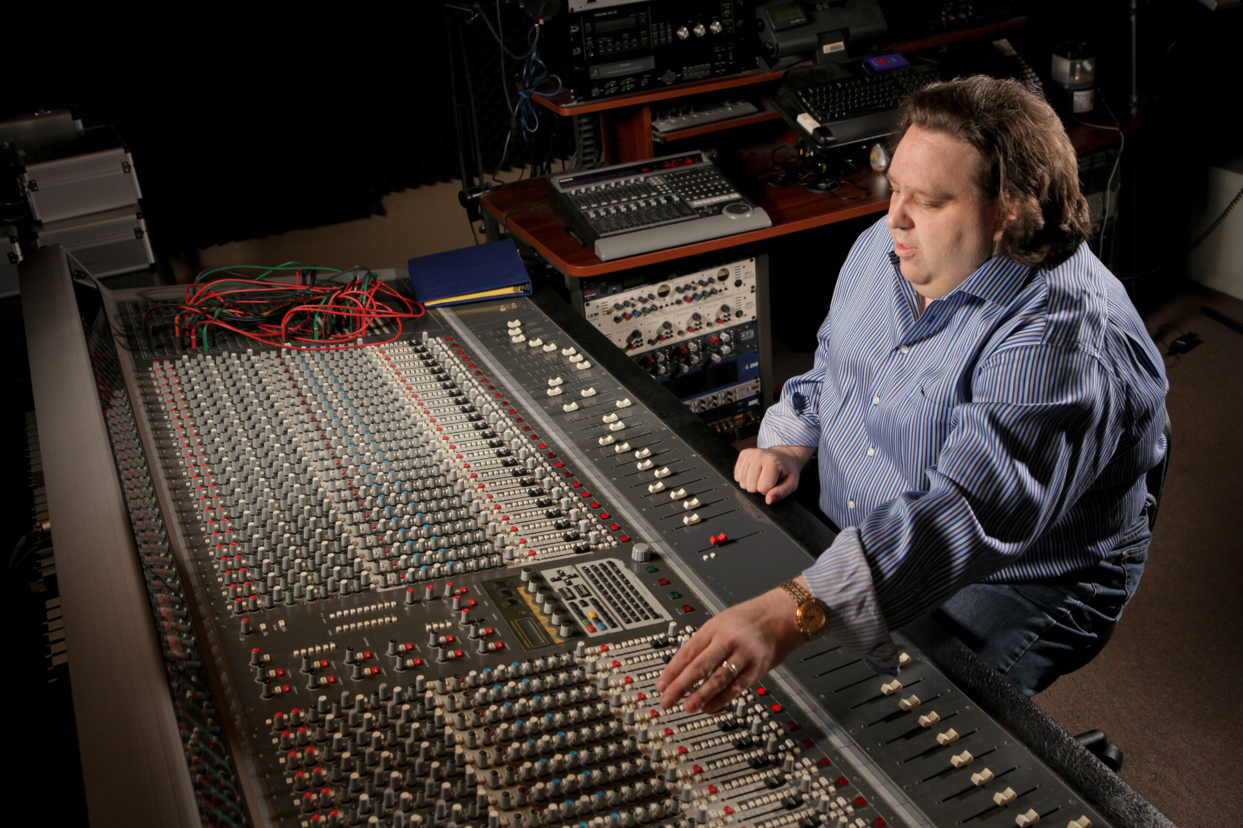 Joey Stuckey seated at the Shadow Sound Studio mixing desk, adjusting studio controls during an audio session.